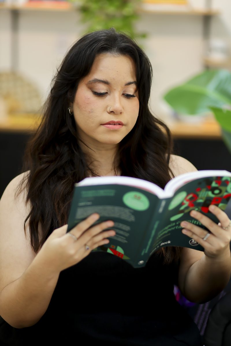 Gabi lendo um livro de terapia cognitivo-comportamental
