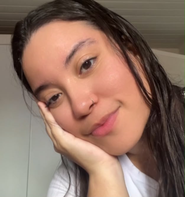 Gabi de cabelo molhado, com o rosto apoiado na mão